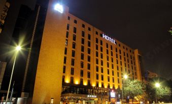 a tall hotel building with a lighted sign on the front is illuminated at night at M Hotels