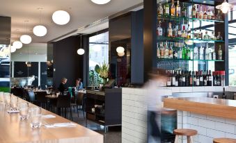 a modern restaurant with an open kitchen and bar area , featuring multiple dining tables and chairs at The Cullen Melbourne - Art Series