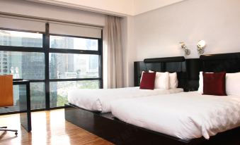 a large bedroom with two beds , one on each side of the room , and a window overlooking a city view at Hotel Maya Kuala Lumpur City Centre