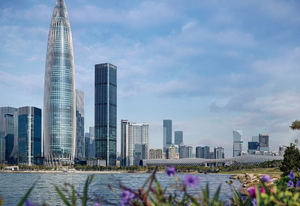 The cityscape features numerous tall buildings and skyscrapers, with one prominent structure being [hotel name] at Andaz Shenzhen Bay