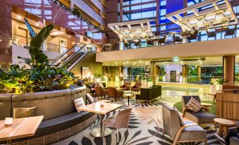 a large hotel lobby with high ceilings , large windows , and various seating areas for guests at Grand Millennium Auckland