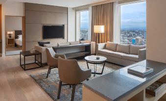 a modern living room with a large flat - screen tv mounted on the wall , a couch , and a dining table at Hyatt Regency Seattle