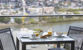 a table with a breakfast setting and a view of the city is shown from a high vantage point at The Milton Brisbane