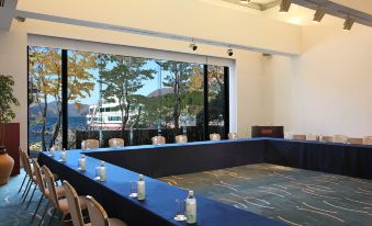 a conference room with a long table , chairs , and a large window overlooking the water at Hakone Hotel