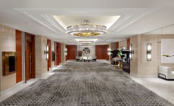 A spacious room is arranged with a decorative ceiling and a central chandelier at Shanghai Marriott Marquis City Centre