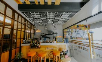 a modern , minimalist café with wooden tables and chairs , a yellow wall , and a large window at Ayaartta Hotel Malioboro