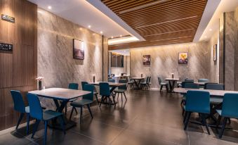 The restaurant features tables and chairs arranged in a central area, facing each other on both sides, fostering a communal dining atmosphere at Mumian Hotel (Guangzhou Baiyun International Airport)