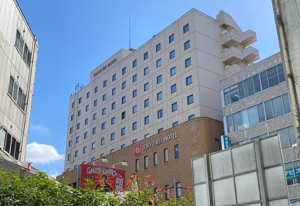 a tall hotel building with a red banner on the side , located in a city setting at Kichijoji Tokyu Rei Hotel
