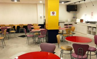 a dining area with yellow and red tables and chairs , along with a counter and refrigerator at 101 Hotel