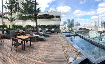 a rooftop pool area with wooden decking , lounge chairs , and a view of the city skyline at Cochin Zen Hotel