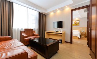 A spacious room on the top floor with a couch, chair, and table in front of the TV at Jinjiang Inn Style (Shanghai Pudong Airport Town)