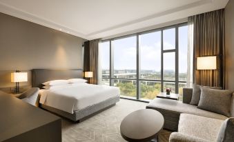 A modern bedroom with large windows and a balcony that offers a view of the city, featuring an unmade bed at Hyatt Place Shanghai Hongqiao CBD