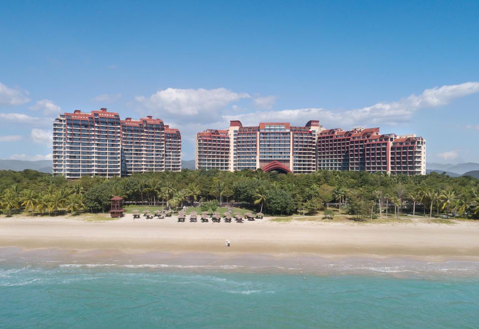 The view from the beach includes buildings and water, with an oceanfront resort in the foreground at Pullman Oceanview Sanya Bay Resort & Spa