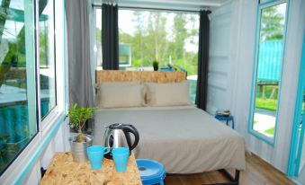 a bed with a wooden headboard and white sheets is in a room with blue curtains at Sarang by the Brook