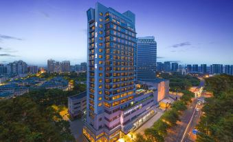 A well-lit large building with numerous windows is accompanied by a neighboring skyscraper at Kasion K Hotel Yiwu