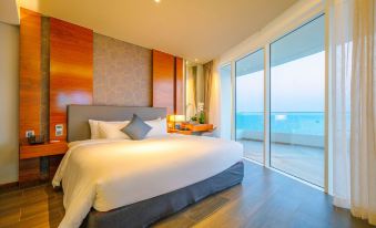 a large bed with white sheets and a gray headboard is in a room with wooden walls , and sliding glass doors leading to an ocean view at Seashells Phu Quoc Hotel & Spa