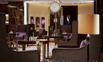 a luxurious living room with a large clock on the wall , several chairs , and a couch at Waldorf Astoria Berlin
