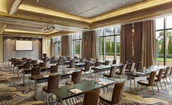There are rows of tables in a spacious meeting room with windows on the side for conducting meetings at Studio City Hotel