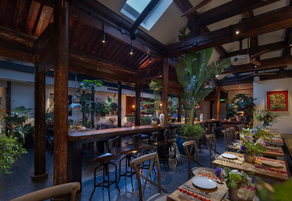The restaurant is furnished with tables and chairs, and there are plants in the center area, while the other rooms are occupied at Peking Yard  Boutique Hotel