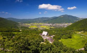 a picturesque view of a mountainous landscape with a small village nestled in the valley at Yufuin Bath Satoyamasafu
