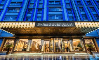 At night, a hotel entrance is adorned with an illuminated sign above its glass door at Byland Star Hotel (Yiwu International Trade City)