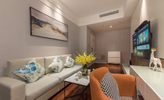 a modern living room with a white couch , orange chair , and a large painting on the wall at Suisse Apartment Hotel Suzhou Jinji Lake Expo Center