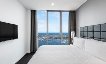 a bedroom with a large window overlooking the ocean and a bed with white linens at Meriton Suites Southport