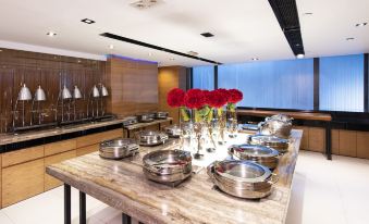 The kitchen features spacious, long tables in the center, accompanied by an open dining area that offers plenty of seating choices at Empire Hotel Hong Kong - Causeway Bay