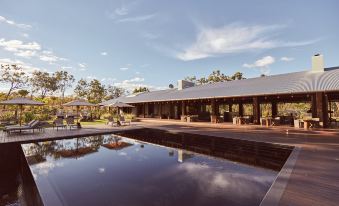 a large wooden building with a pool in front of it , surrounded by trees and grass at Mt Mulligan Lodge
