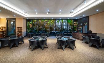 a modern lounge area with black chairs and tables , surrounded by glass walls and plants at Millennium Harbourview Hotel Xiamen