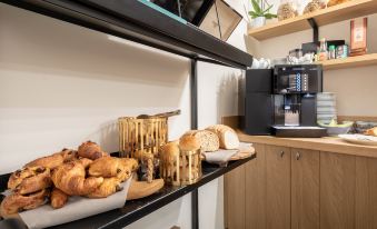 a dining area with a variety of pastries and breads on display , along with a coffee maker and microwave at Hotel Carlton