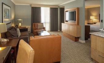a hotel room with a large flat - screen tv mounted on the wall , a couch , and a dining table at DoubleTree by Hilton Hotel Pittsburgh - Green Tree