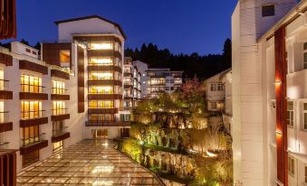 a modern building with multiple floors and balconies is illuminated at night , surrounded by greenery at Alishan House