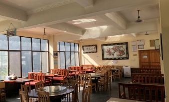 The hotel's ground floor features a spacious restaurant adorned with large windows, multiple tables, and an empty dining area at Tina's Youth Hostel