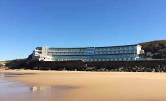 a large hotel building situated on the beach , with a clear blue sky above at Arribas Sintra Hotel