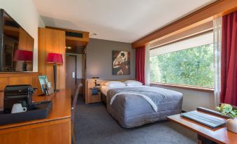 a cozy bedroom with a large bed , a desk , and a window overlooking the outdoors at Van der Valk Hotel Volendam