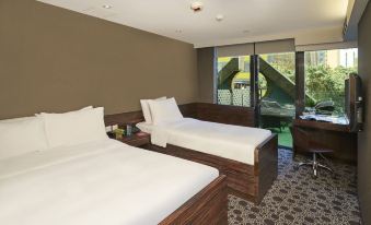 There is a bedroom with two beds and an open window that provides a view of another area at J Link Hotel