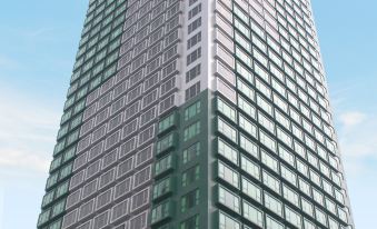 In front of an office tower, there is a tall building with many windows on its side at Hotel COZI Harbour View