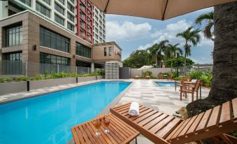 a rooftop pool area with lounge chairs , umbrellas , and a wooden lounge table under an umbrella at Travelodge Ipoh