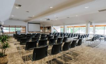 a conference room with rows of chairs and a projector screen at the front , ready for a meeting or presentation at Edgewater Hotel