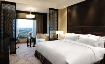 a large , well - lit hotel room with a white bed , black curtains , and a view of the city at Crowne Plaza New Delhi Mayur Vihar Noida
