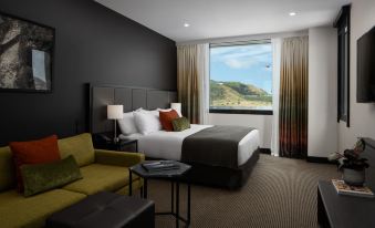 a modern hotel room with a large bed , couch , and window offering a view of the outdoors at Rydges Wellington Airport, an EVT hotel