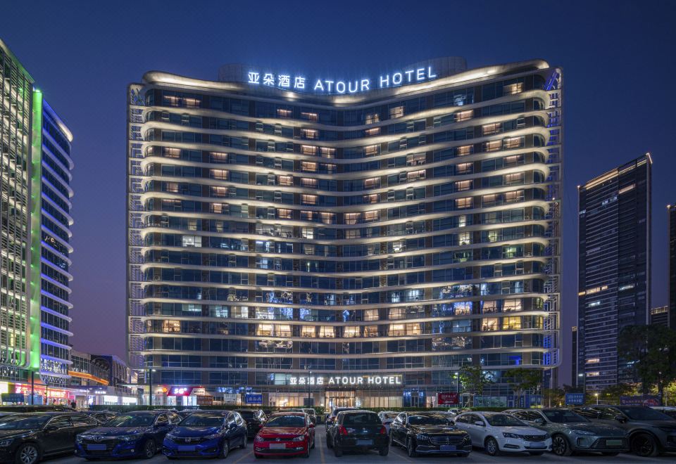 The hotel building is illuminated with neon lights at night at Atour Hotel Shunde Happy Coast Foshan
