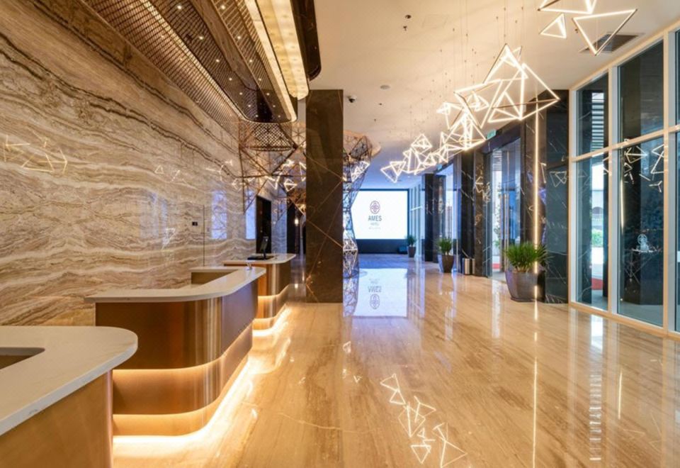 a modern hotel lobby with a marble floor , gold accents , and modern furniture , as well as a large tv screen at Ames Hotel