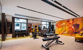 A spacious room with multiple exercise equipment and a centrally located indoor gym at Hampton by Hilton