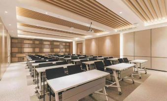 In a spacious room, rows of tables are arranged in front, while the far wall remains empty at Atour Hotel (Yiwu International Trade City)