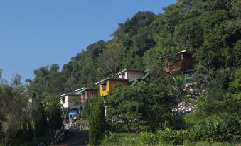 a row of colorful houses on a hillside , surrounded by trees and greenery , with clear blue skies above at Jsi Resort