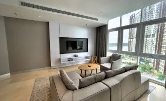 a modern living room with a large flat - screen tv mounted on the wall , a couch , and a dining table at Fraser Place Puteri Harbour, Johor