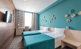 a hotel room with two beds , a desk , and blue walls decorated with wall art at Diplomat Hotel