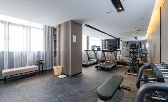 a well - equipped gym with various exercise equipment , including treadmills and weightlifting machines , in a spacious room with large windows at Atour Hotel